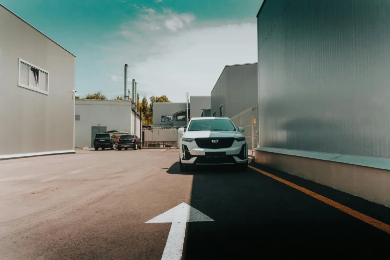 the front end of a white car parked next to a building