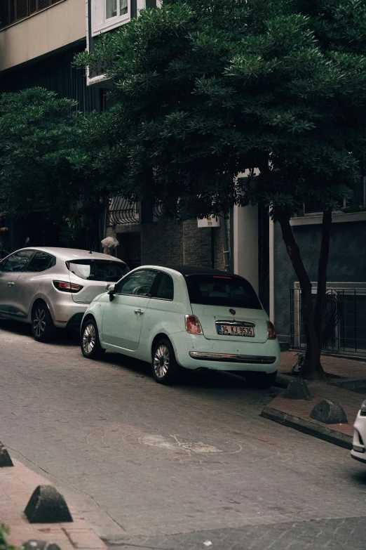 two small cars parked on the side of a city street