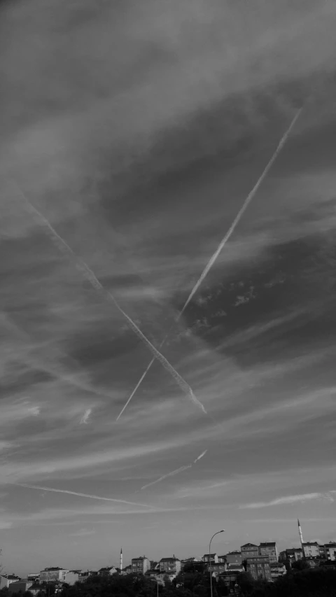 four contrails in a cloudy sky above the water