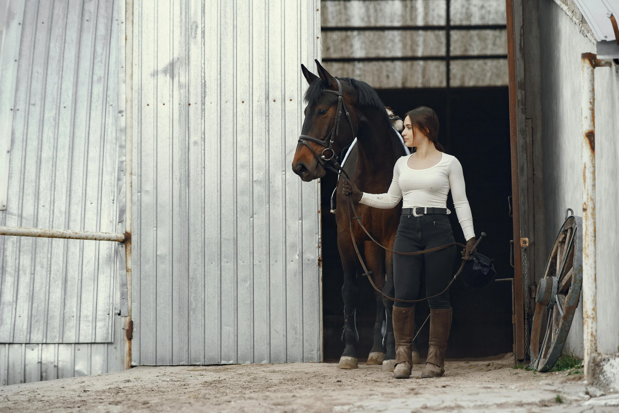 a woman in a white top is standing with a horse