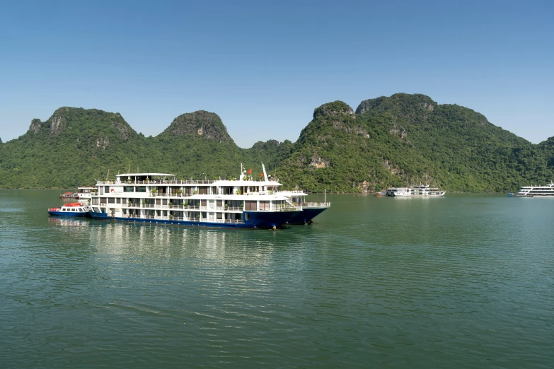 a large boat traveling through water with mountains in the background