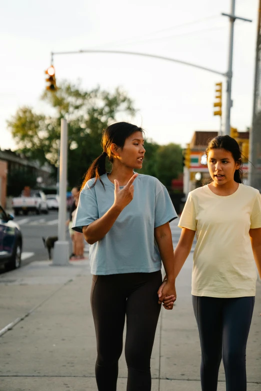 two women standing on the side of a street holding hands