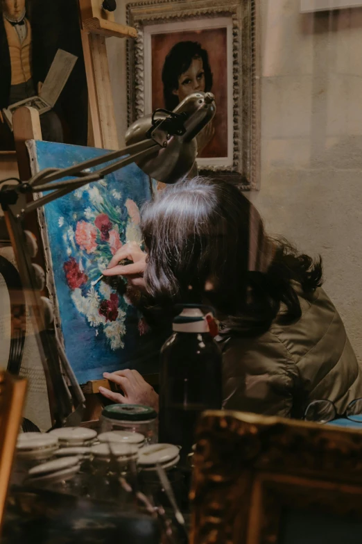 a woman looking at an art piece while sitting at a table