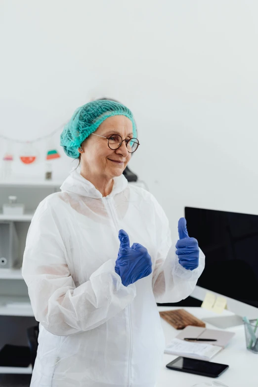 a lady with blue gloves giving a thumbs up