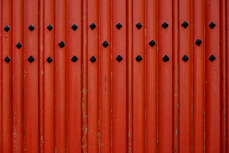 a red wall is covered with small black holes