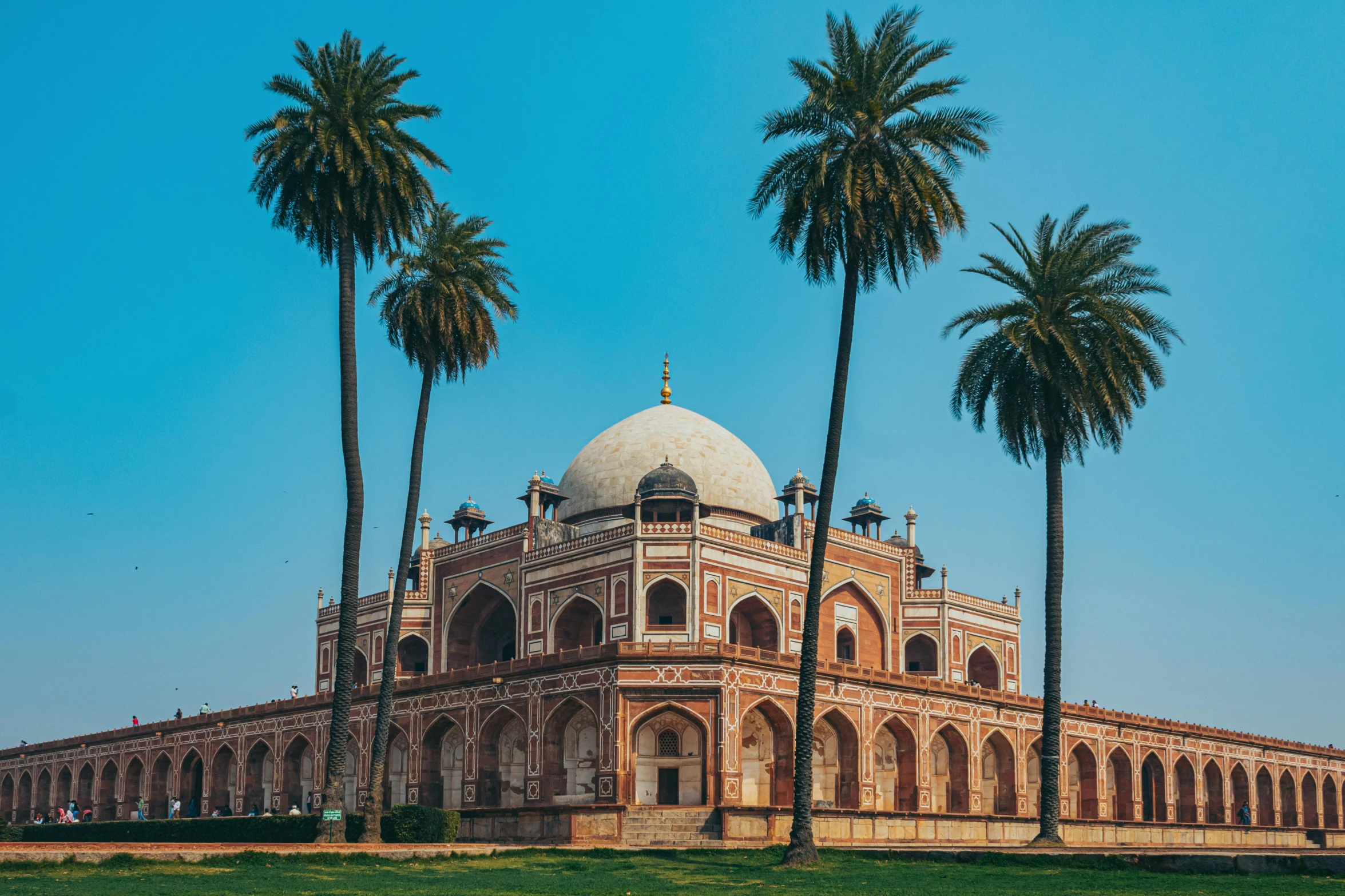 an ornate building surrounded by palm trees with a dome in front