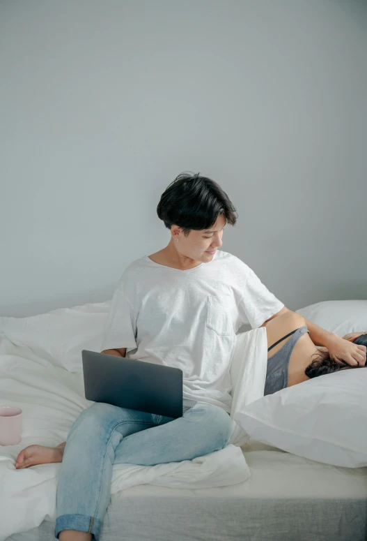 a woman sitting on a bed with a laptop