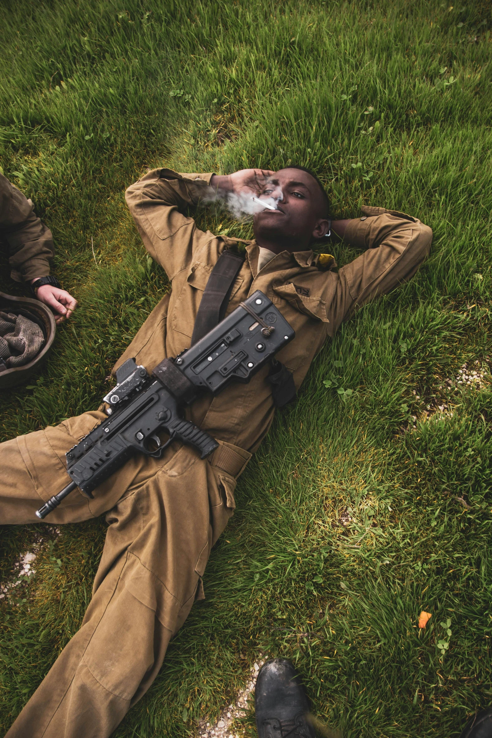 a man laying on grass holding a gun