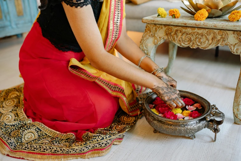 a woman in red dress sitting and tying string on wristlet