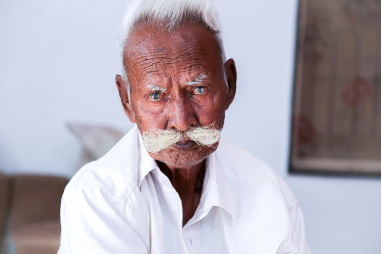 an old man with a moustache and a mustache looks at the camera