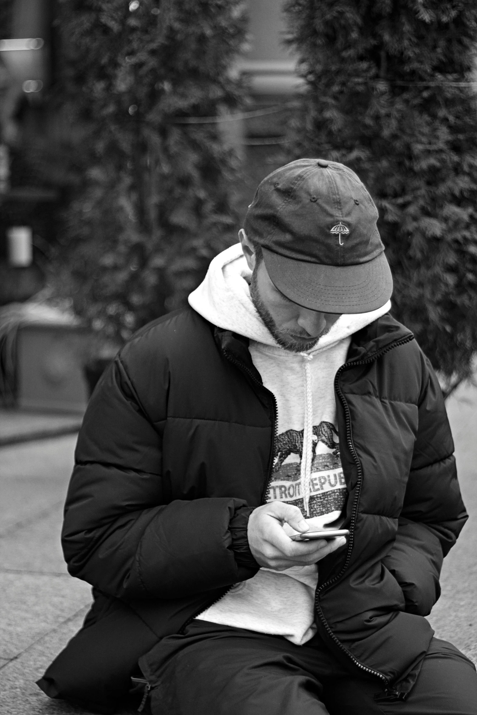 man sitting on a curb looking at a phone