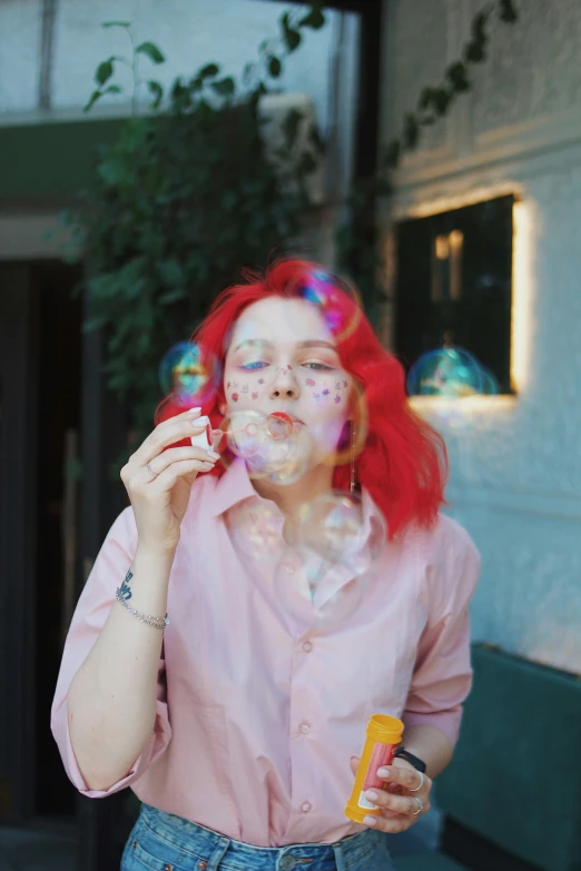 a woman in pink shirt blowing soap on her face