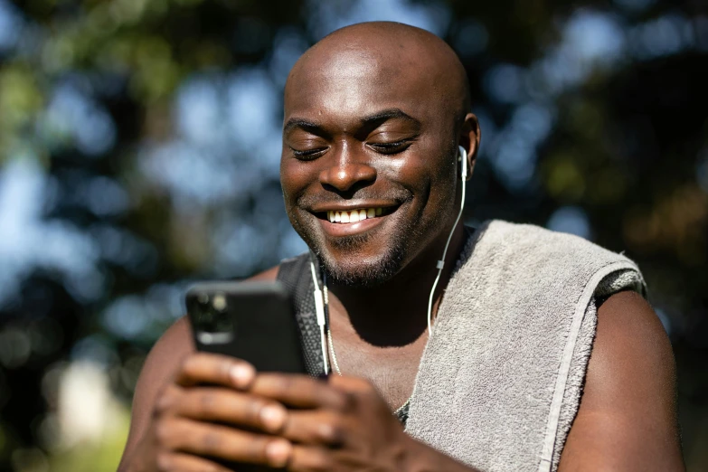 a smiling man with earphones is looking at his phone