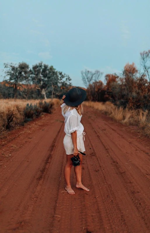 a young lady standing on the road with her hat on