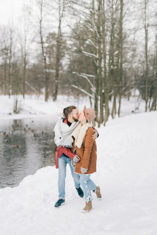 two women are standing in the snow near a river