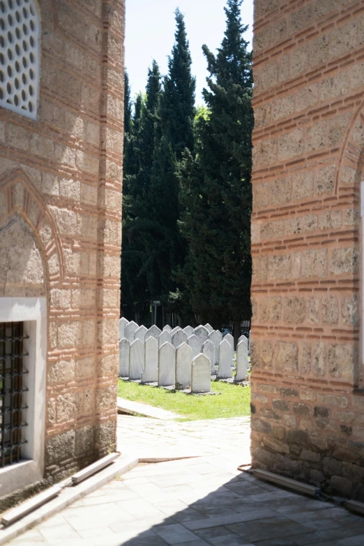 an archway way with a stone wall leading to some tombstones