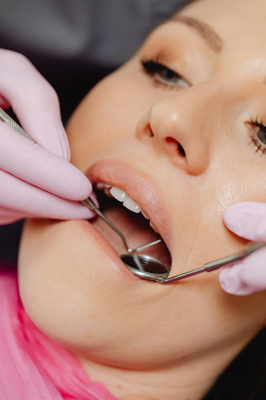 a woman getting her teeth checked by dentists