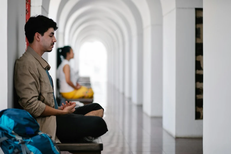 a man sitting on the ground in a building looking at a person standing next to him