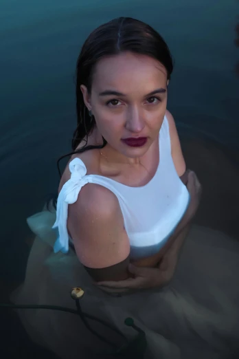 a woman in a white top poses by the water
