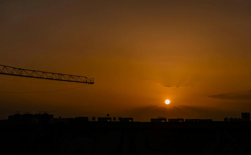 the sun is setting in the horizon, surrounded by buildings