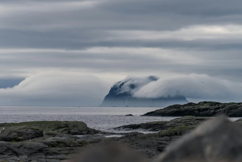 a hill is above the water near some rocks