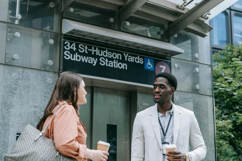 man standing next to a woman in front of subway station