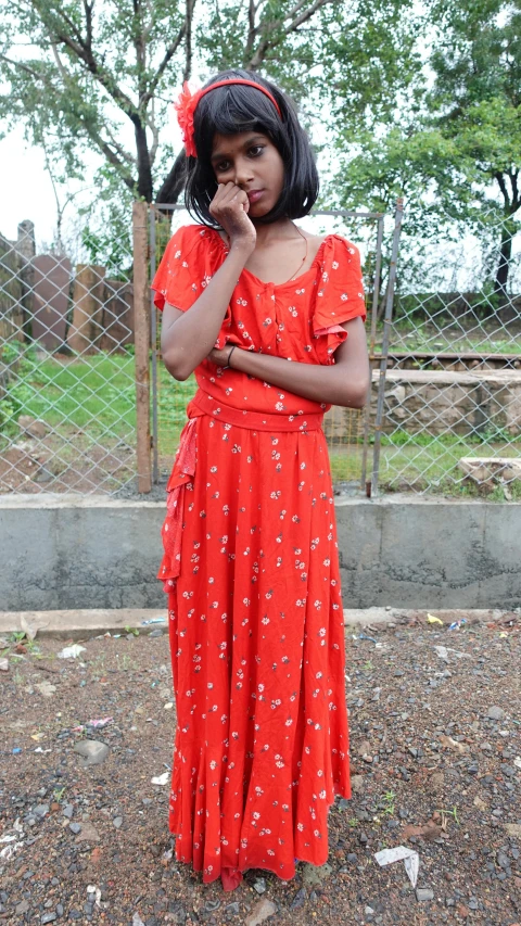 a woman in a red dress is standing in a field