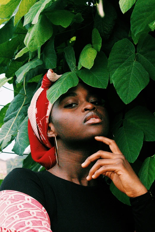 a girl leaning against a tree and wearing a scarf