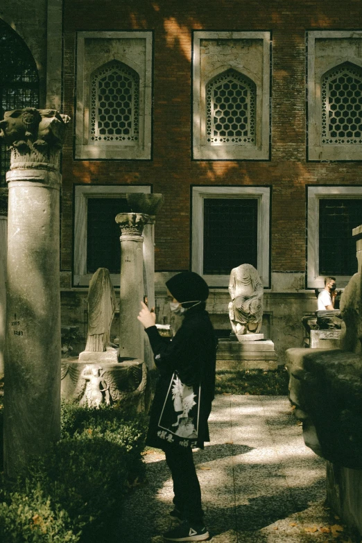 a woman in a hat looking at sculptures outside a building