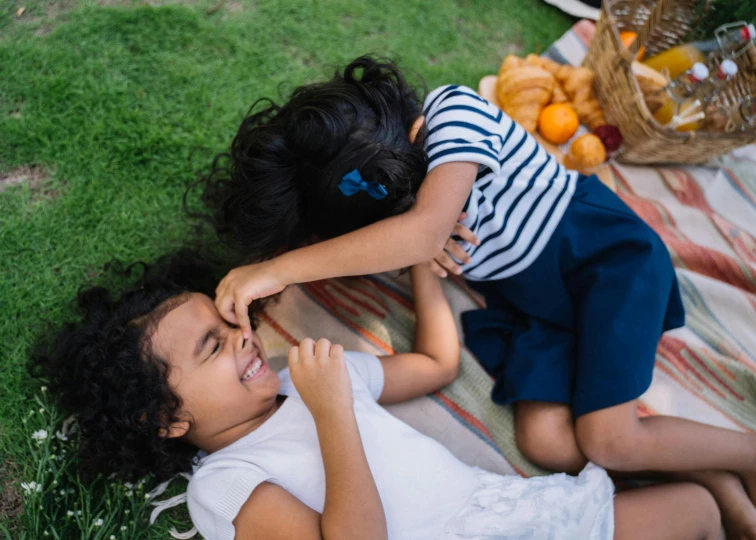 two small children laying on the grass playing together