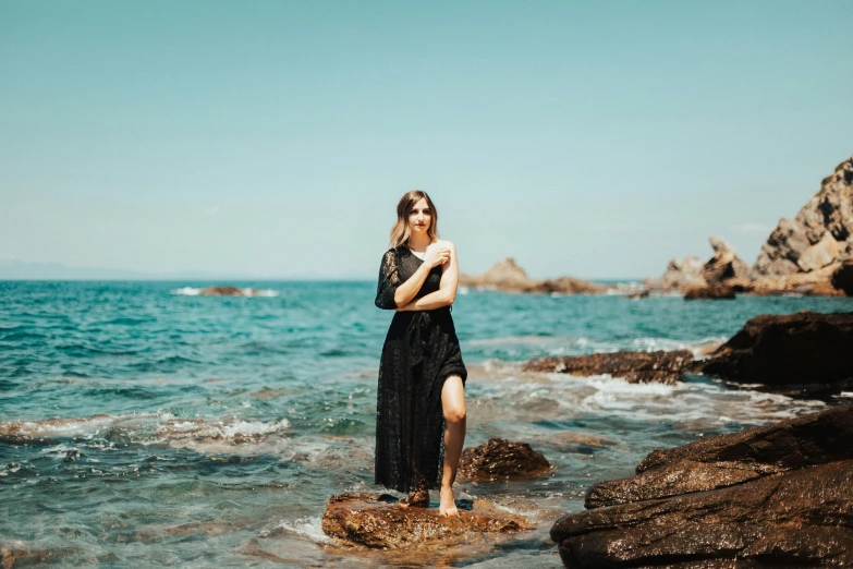 a woman is standing on rocks in the water