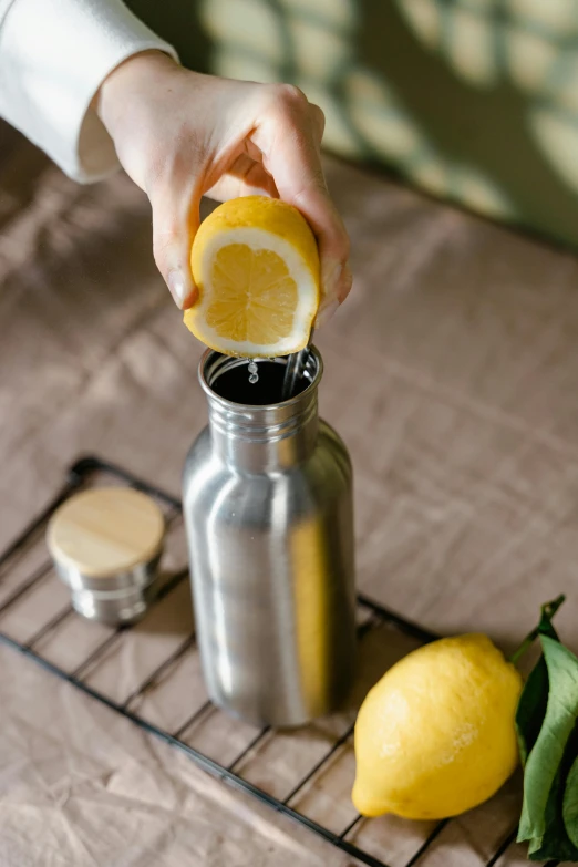 someone squeezing lemon juice into a mason jar