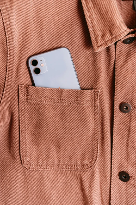 a cellphone sticking out of a pocket in a brown shirt