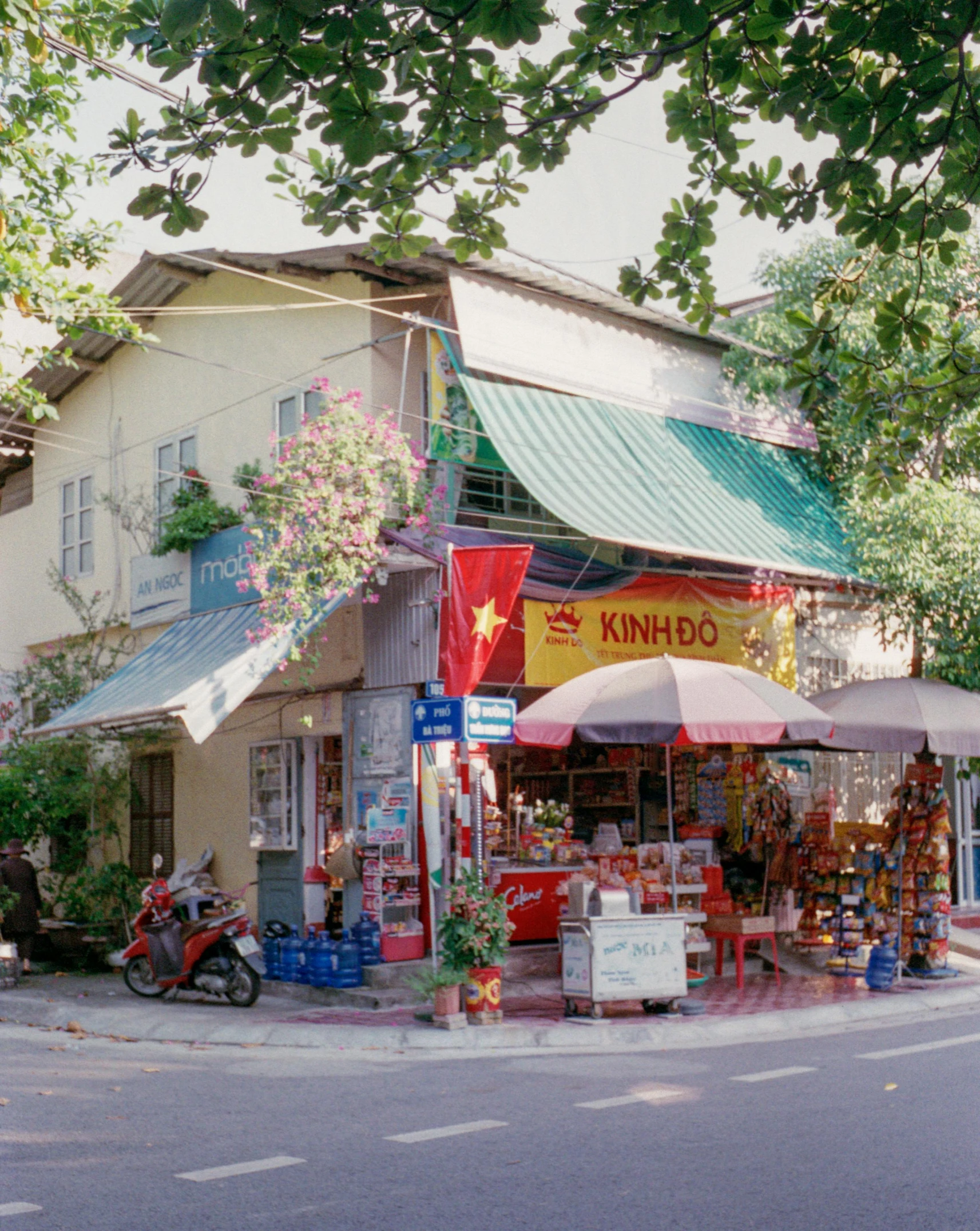 an outside street corner with umbrellas and small shops