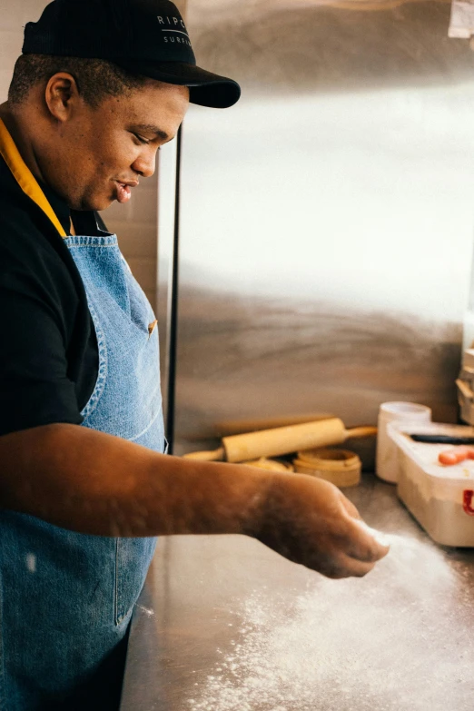 a man in an apron and hat is baking on a pan