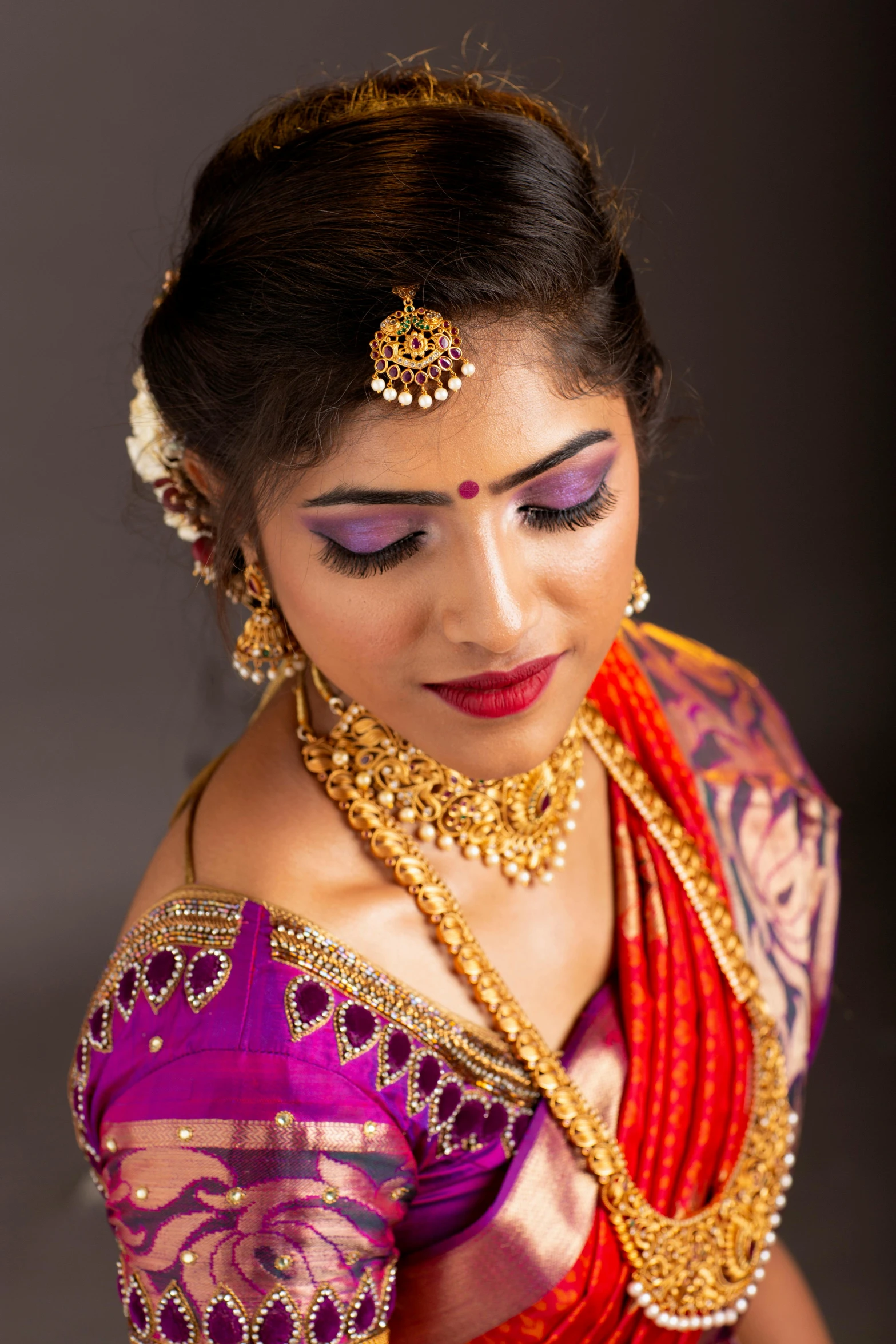 a woman wearing gold jewelry and a pink top