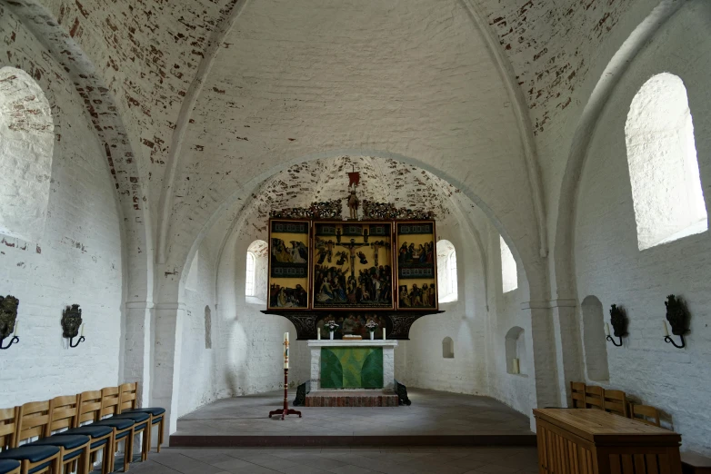 an empty church with pews and paintings on the walls