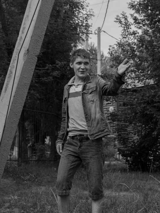 a boy stands in a field holding his arm out