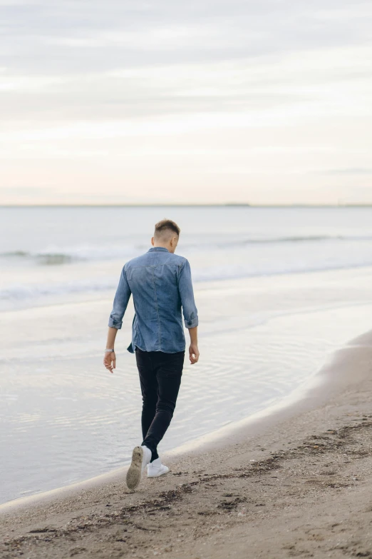 there is a man walking along the beach