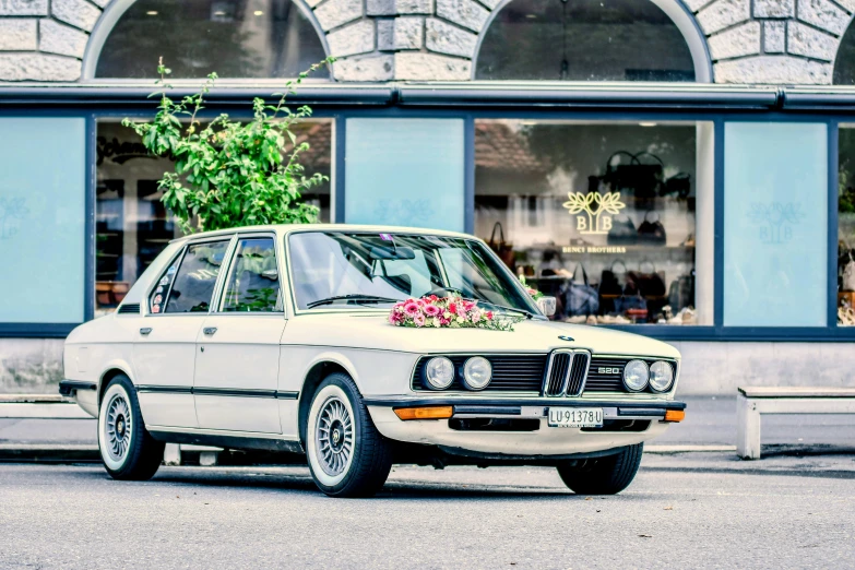 a white car with a bunch of flowers on the hood