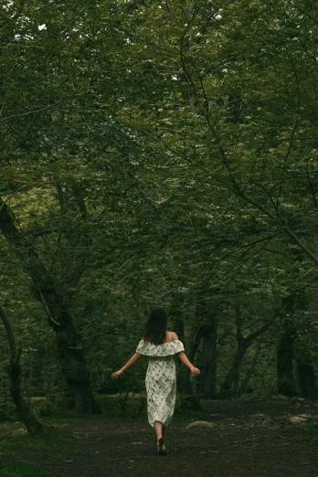 a woman walking along a forest path in the grass