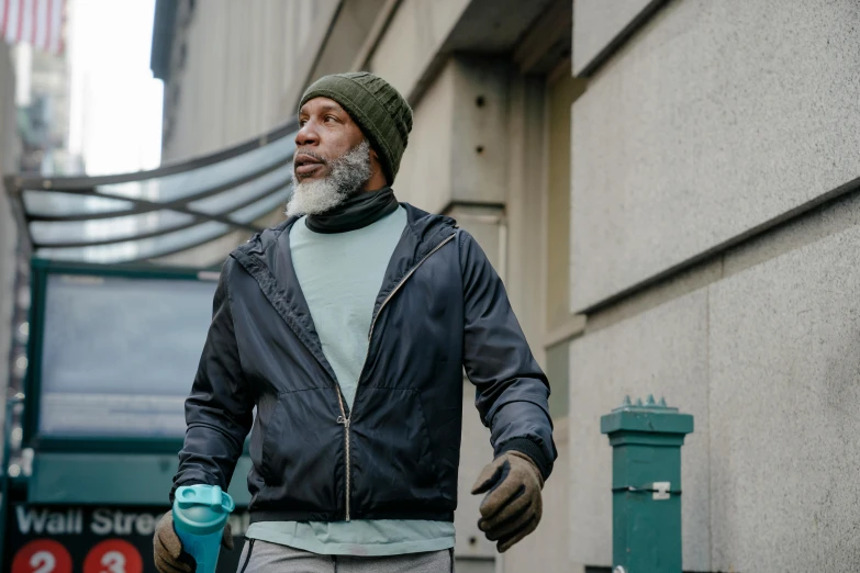 a man with a beard and a sweater walks down the street