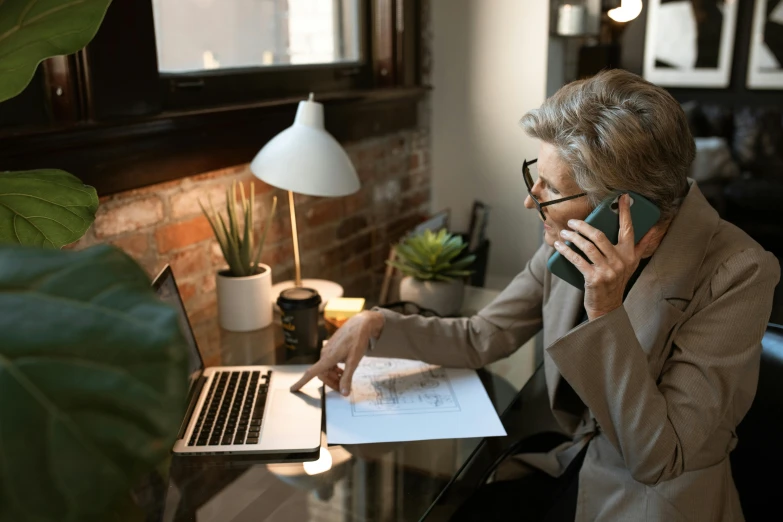 the woman is on her cell phone while at the computer