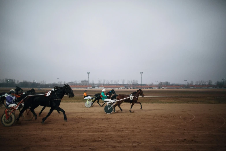 a group of horses riding on top of a dirt field