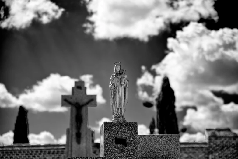 a cemetery and a statue in the foreground with clouds in the background