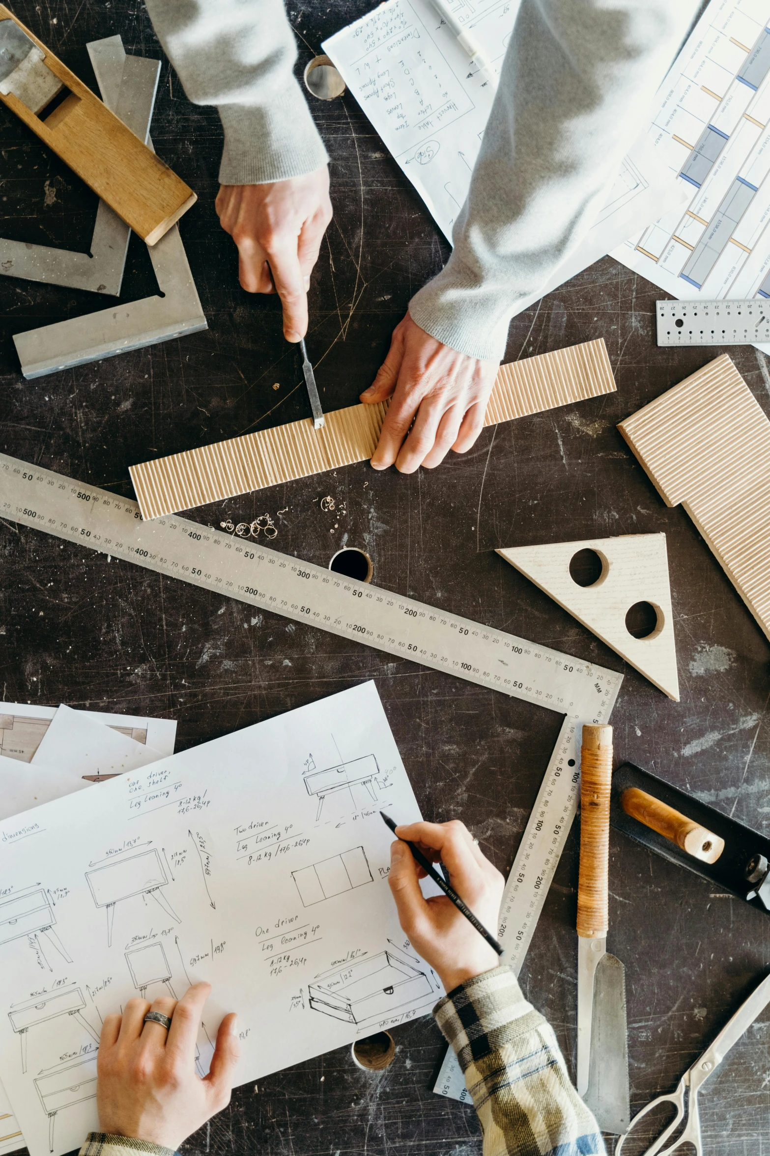 several people are using rulers to cut paper on a table