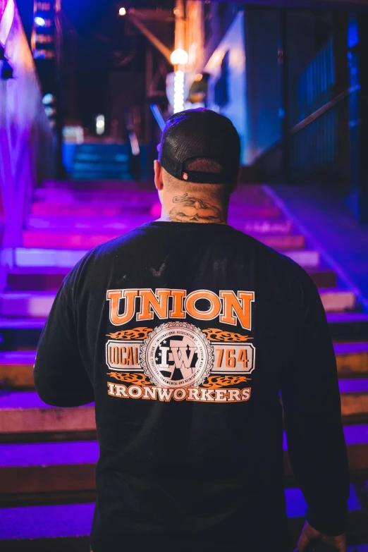 the back of a man wearing a black united television crew shirt