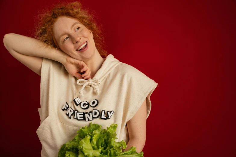 a woman with red hair holding a green leafy vegetable