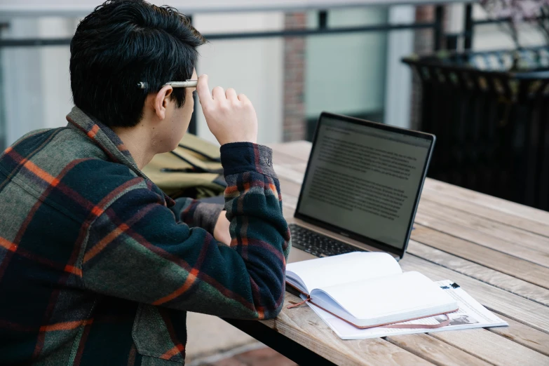 the man is sitting outside using his laptop