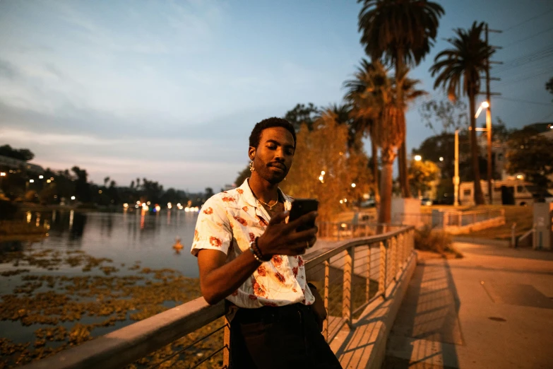 a man is standing on the edge of a bridge and using his cell phone